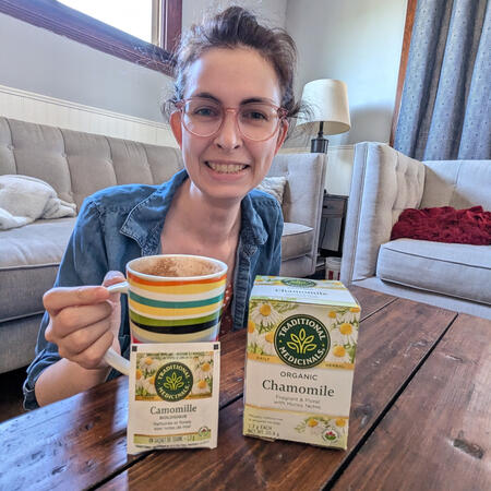 Smiling women is drinking chamomile tea with the tea box in view
